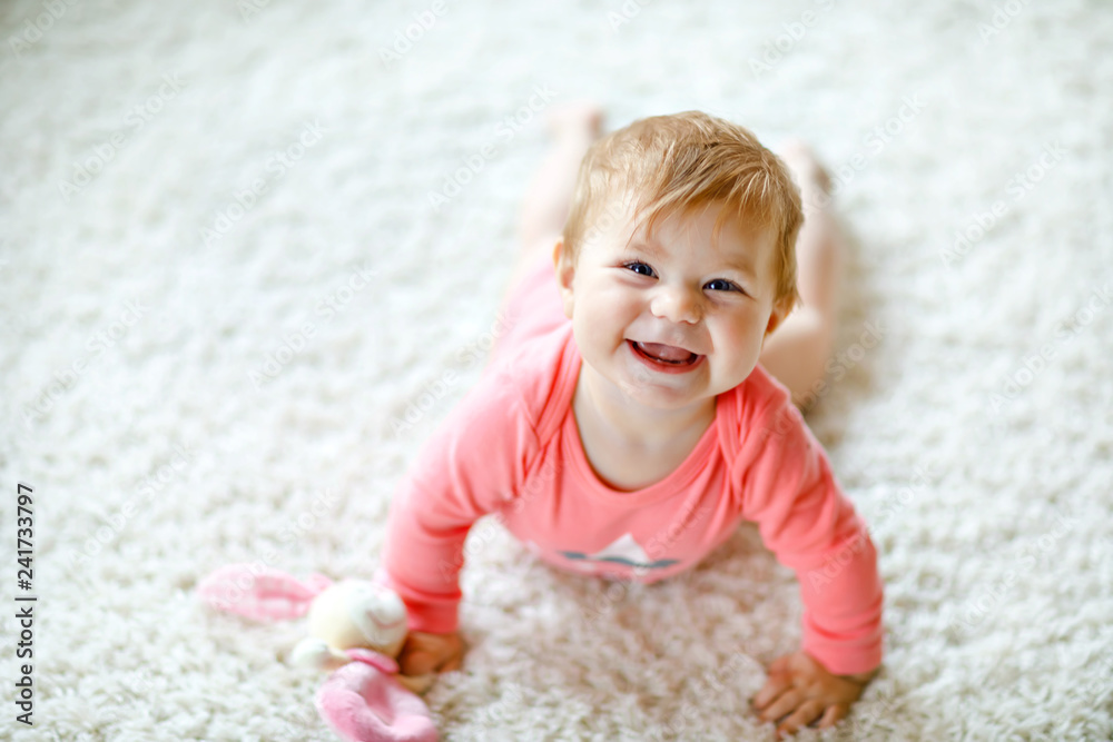 Little cute baby girl learning to crawl. Healthy child crawling in kids room with colorful toys. Back view of baby legs. Cute toddler discovering home and learning different skills Little cute baby girl learning to crawl. Healthy child crawling in kids room with colorful toys. Back view of baby legs. Cute toddler discovering home and learning different skills