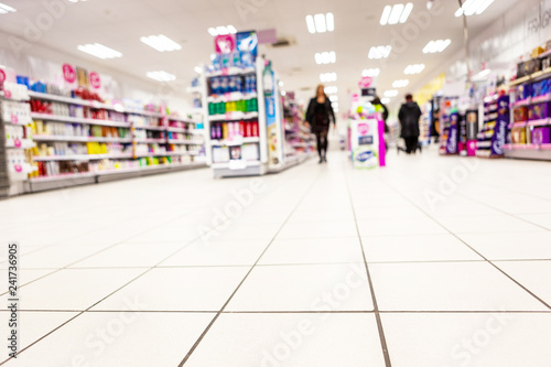 Abstract background blurred photograph of an aisle with shelves in bright modern drugstore at supermarket shopping center