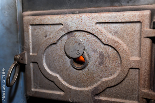 Door hole for monitorising the fire close up shot on wood central heating system , visible flame in the background.