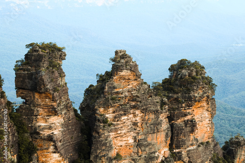Close view of the Three Sisters in Katoomba with a valley of the Blue Mountains in the background (Sydney, New South Wales, Australia)