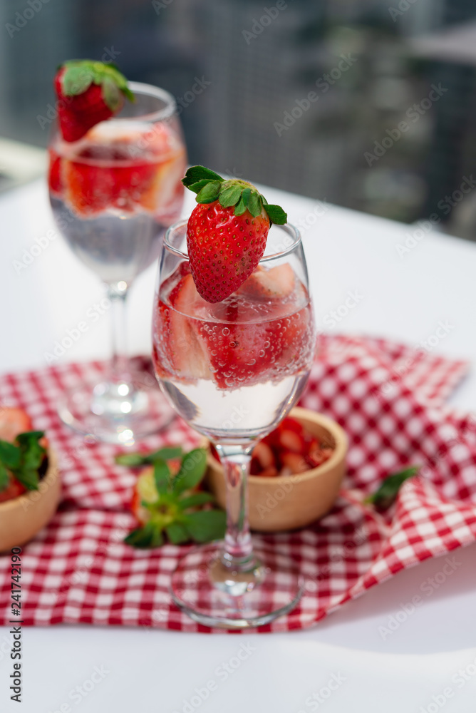 Glass of strawberry cocktail soda placed on a plaid tablecloth . Glass of strawberry cocktail soda placed on a plaid tablecloth .