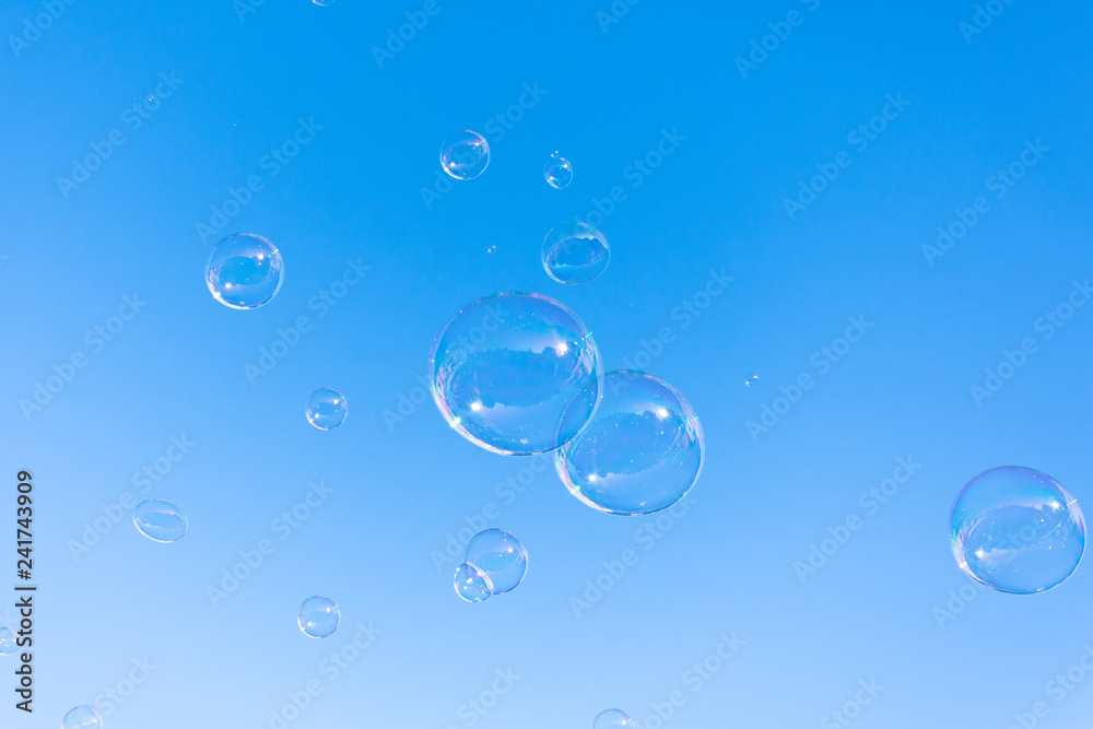 Soap bubble fly on blue sky background.