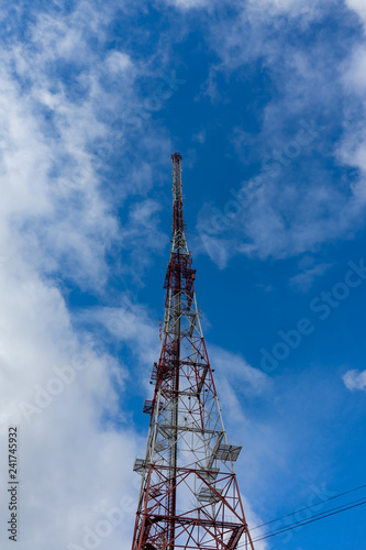 Antenna tower with blue sky and cloud background.