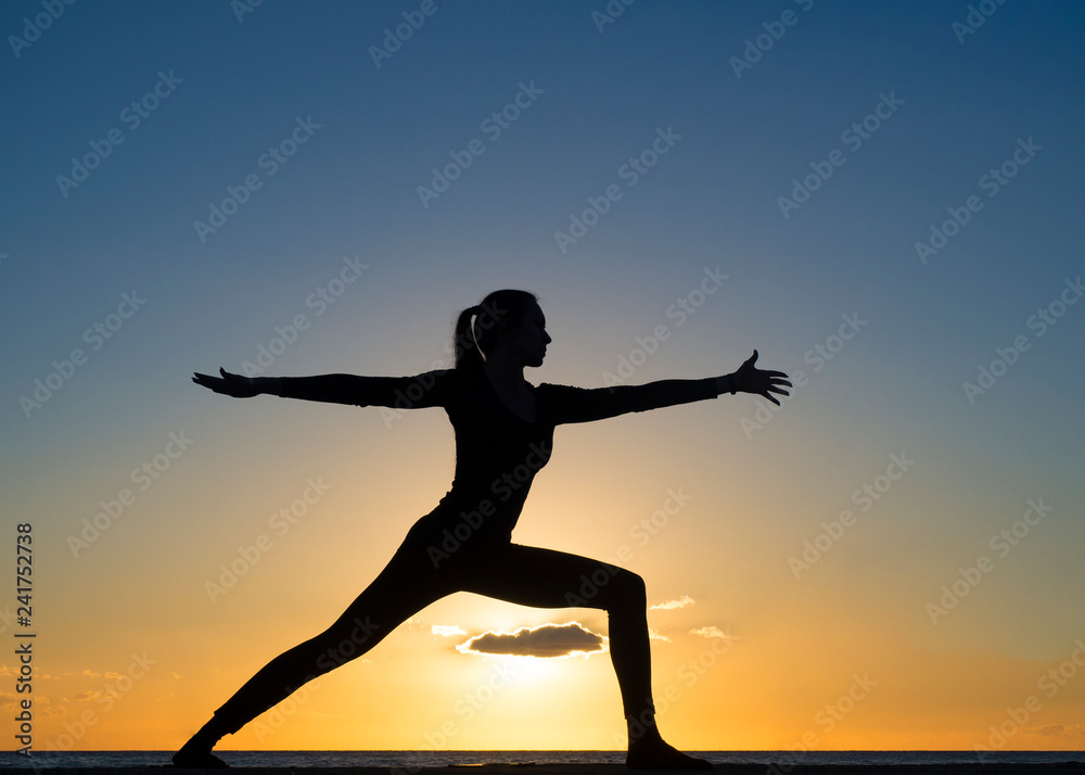 Silhouette young woman practicing pose yoga on swimming pool and the nature beach at sunset or sunrise. Yoga and Healthy Concept