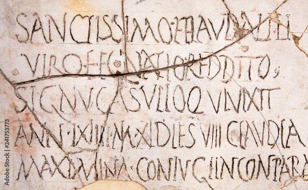 Latin inscriptions background wallpaper on an ancient cracked marble slab in Rome.