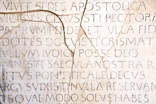 Fotografie, Obraz Latin inscriptions background wallpaper on an ancient cracked marble slab in Rome