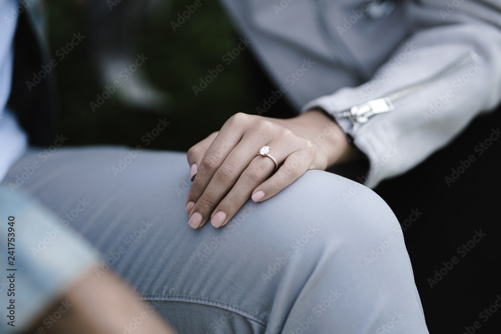 Close up of woman's hand with ring on man's lap Close up of woman's hand with ring on man's lap