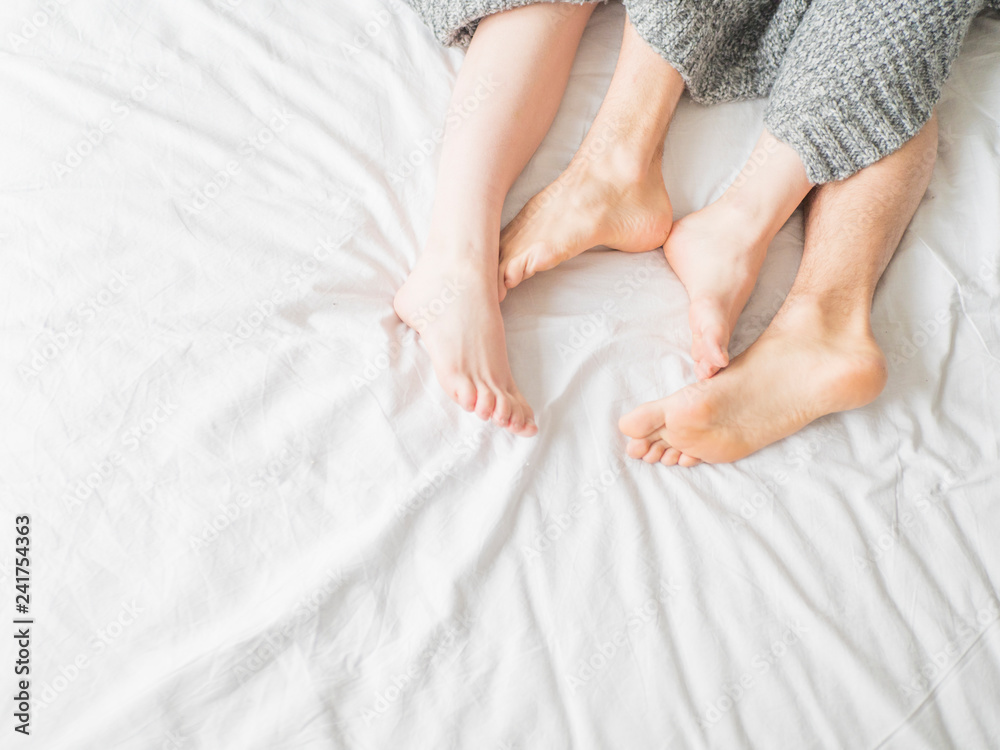 Feet of two couple sleeping on bed under blanket. Love and relationship concept Feet of two couple sleeping on bed under blanket. Love and relationship concept