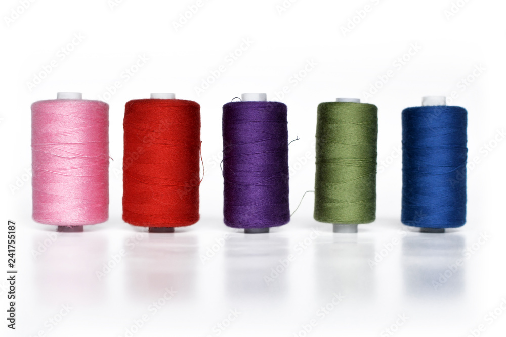 Different colorful reels with sewing yarn in a row isolated on white background Different colorful reels with sewing yarn in a row isolated on white background