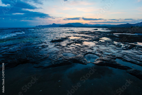 Rocky shore washed by sea waves in evening. Marine landscape
