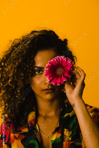 Woman holding transvaal daisy against yellow background photo