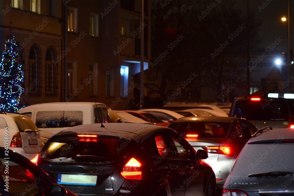 Cars standing in row in traffic jam on city street on slippery snowy road in winter