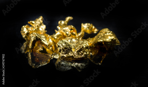 Several gold nuggets on a dark background. Selective focus.