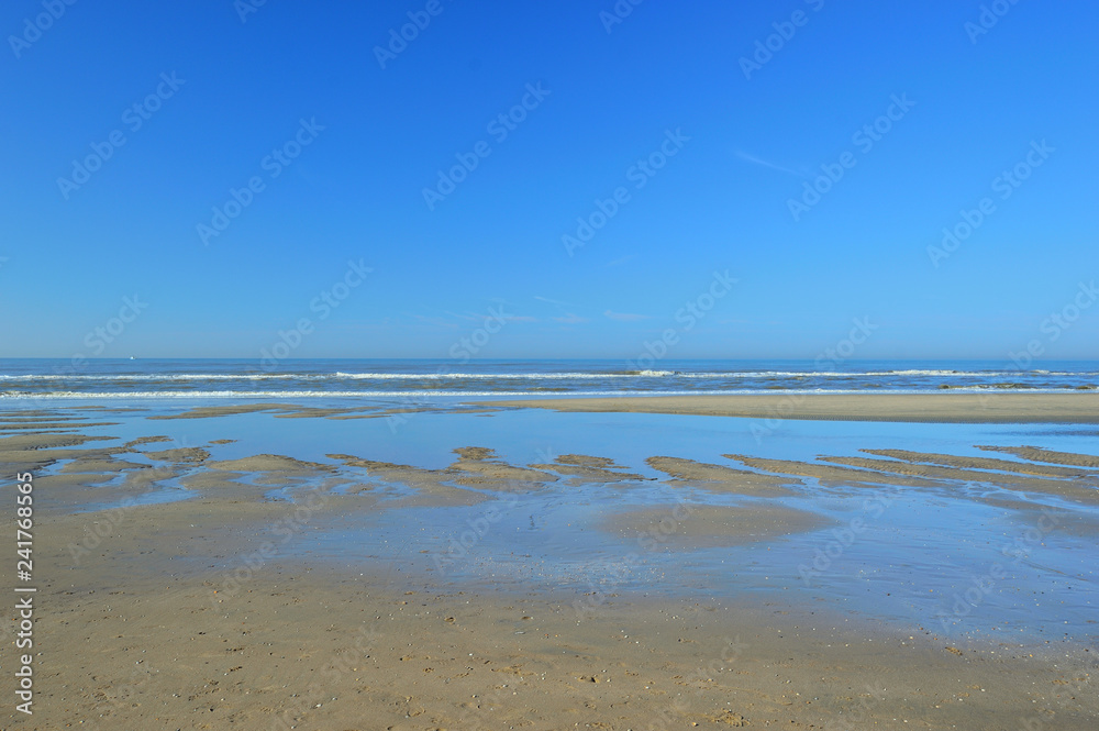 Wybrzeże morza i piaszczysta plaża pod błękitnym niebem.