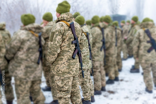 a detachment of soldiers with Kalashnikov assault rifles stand in formation to prepare for battle and offensive. photo