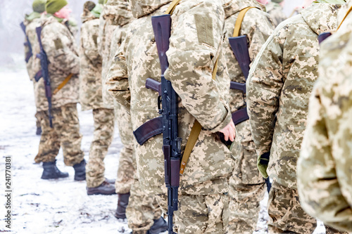 a detachment of soldiers with Kalashnikov assault rifles stand in formation to prepare for battle and offensive.