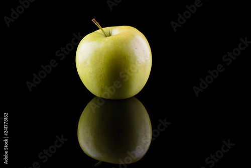 Green apple variety Golden on a black background with reflection