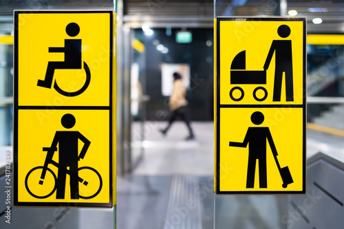 handicapped, bicycle, stroller and big luggage yellow pictrogram in metro, information in public transport, blurred person in the background