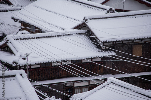 Thin layer of fresh snow covers roves of old wooden Japanese houses photo