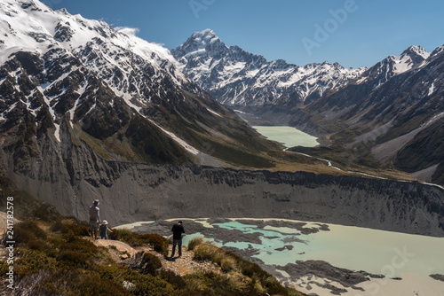 Hikers taking in the view from the top of the Tarns Track up the Hooker valley to Mount Cook, Mueller Lake in the foreground. Aoraki/Mount Cook National Park, New Zealand. photo