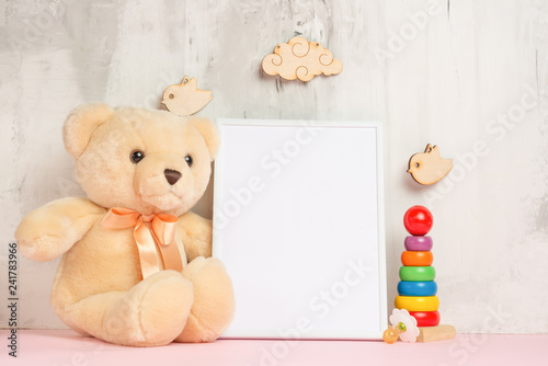 Children's toys, a teddy bear and a frame on a light wall background, for design, layout. Baby shower © Anton