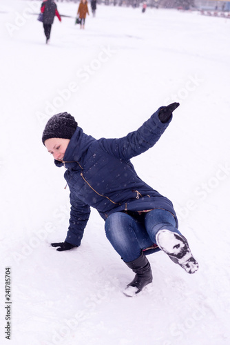 The girl slipped on ice covered with snow, falling and injury in the winter