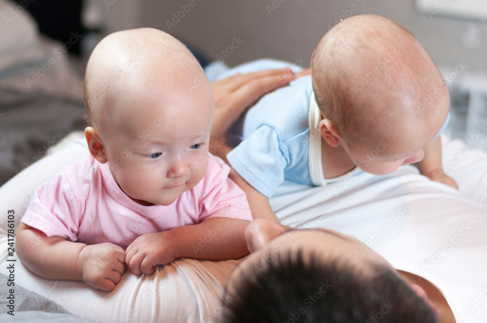 Young father with his newborn twins lying in bed. Selective focus.