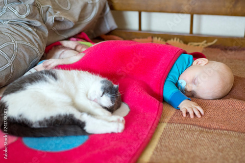 Baby and cat sleep together in the bed © Pavlo
