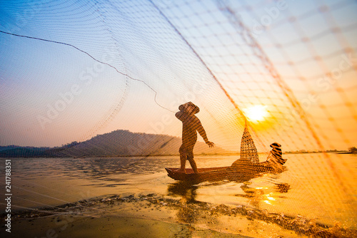 Fisherman on boat river sunset Asia fisherman net using on wooden boat casting net sunset or sunrise in the Mekong river