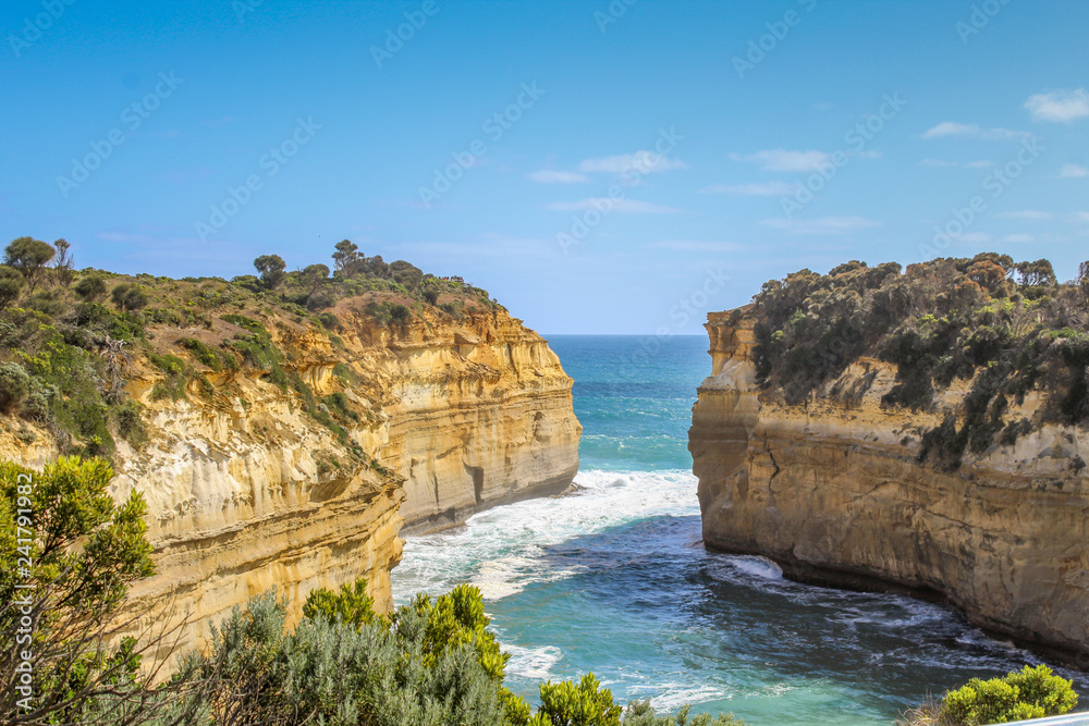 View from top of Loch Ard Gorge without any tourists on a clear summer day with sea breeze, waves and blue sky (Great Ocean Road, Victoria, Australia