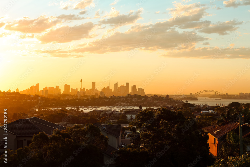 Magical glowing orange sunset over the skyline of Sydney with Harbour Bridge as seen on a summer evening from Dover Heights (Sydney, Australia)