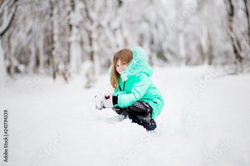 Funny little girl having fun in beautiful park during snowfall