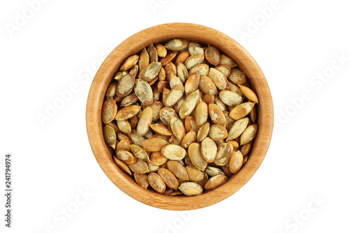 Shelled roasted pumpkin seeds in bamboo bowl on white background