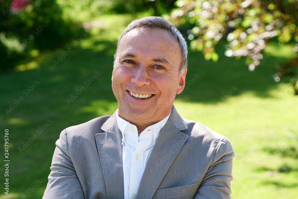 An outdoor portrait of an smiling caucasian man wearing a white shirt, a grey coat. An outdoor portrait of an smiling caucasian man wearing a white shirt, a grey coat.