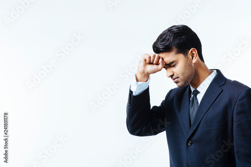 Portrait of a handsome businessman holding his head in disbelief, in pain or meditating, isolated on white background.