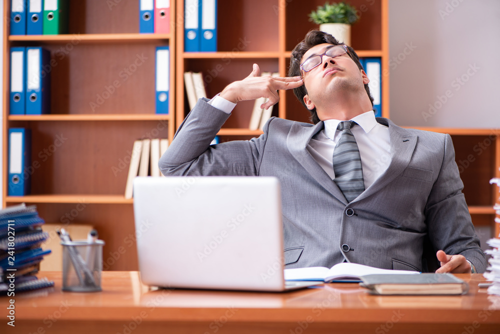Young handsome businessman unhappy with excessive work Young handsome businessman unhappy with excessive work