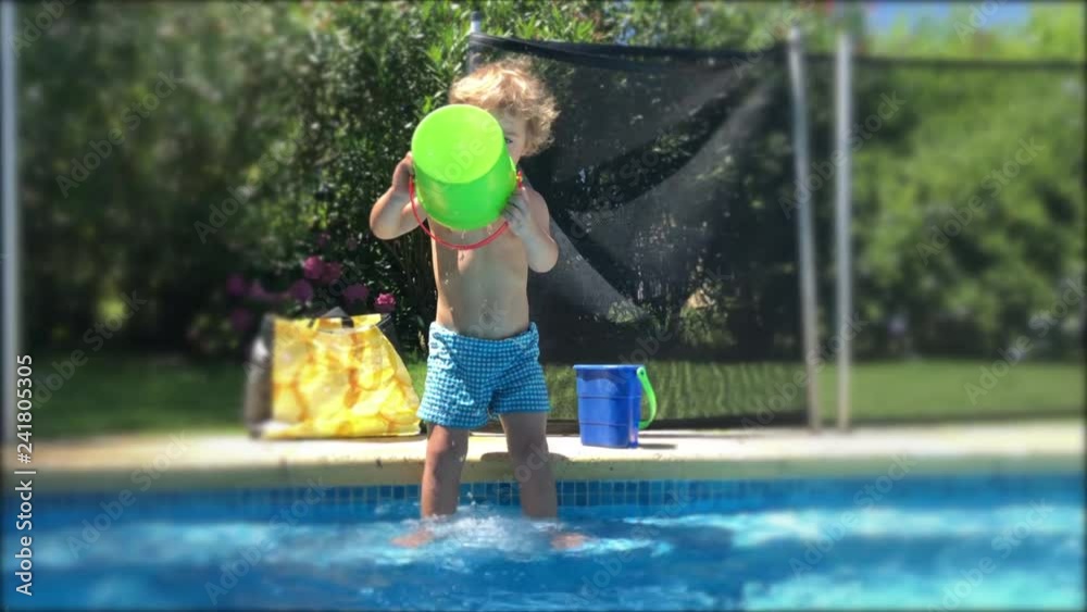 Baby toddler boy playing with bucket and watter at swimming pool