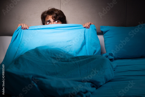 Young man scared in his bed having nightmares photo