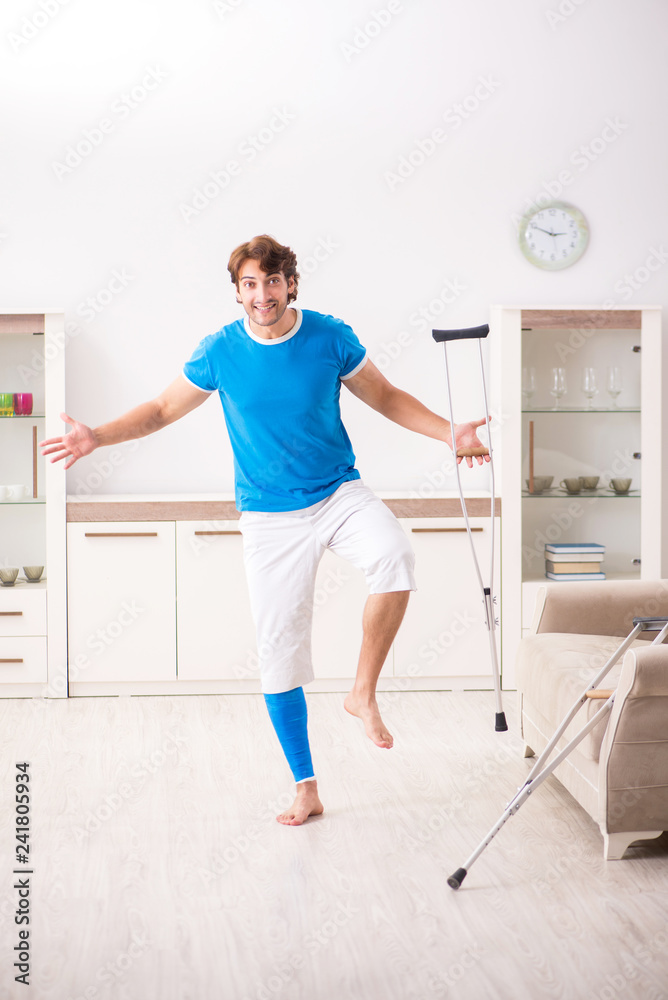 Leg injured young man with crutches at home Leg injured young man with crutches at home