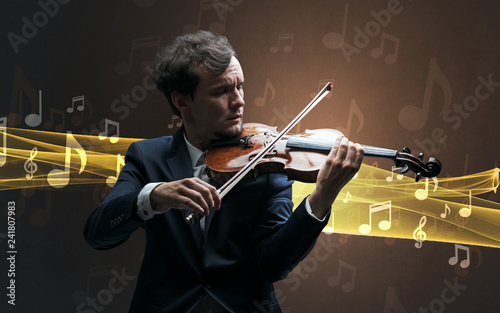 Young male musician playing on his violin with musical notes around photo