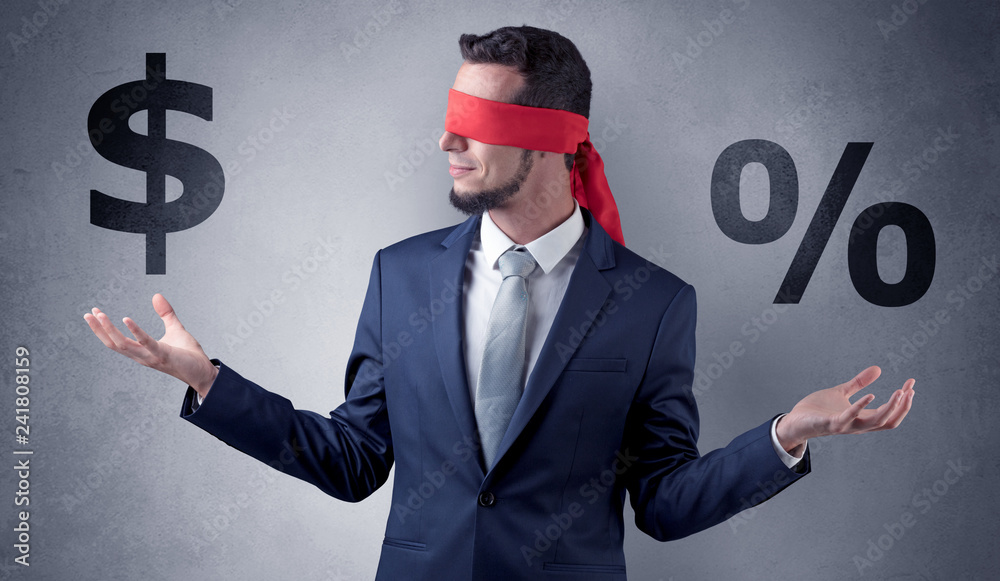 Serious businessmen standing in front of a grey wall with red ribbon on his eye, holding dollars
Serious businessmen standing in front of a grey wall with red ribbon on his eye, holding dollars