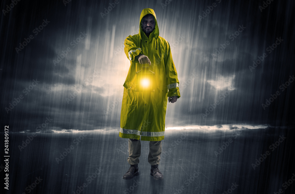 Fototapeta premium Raincoated man walking in storm with glowing lantern in his hand 