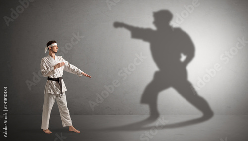 Young karate man confronting with his own shadow 