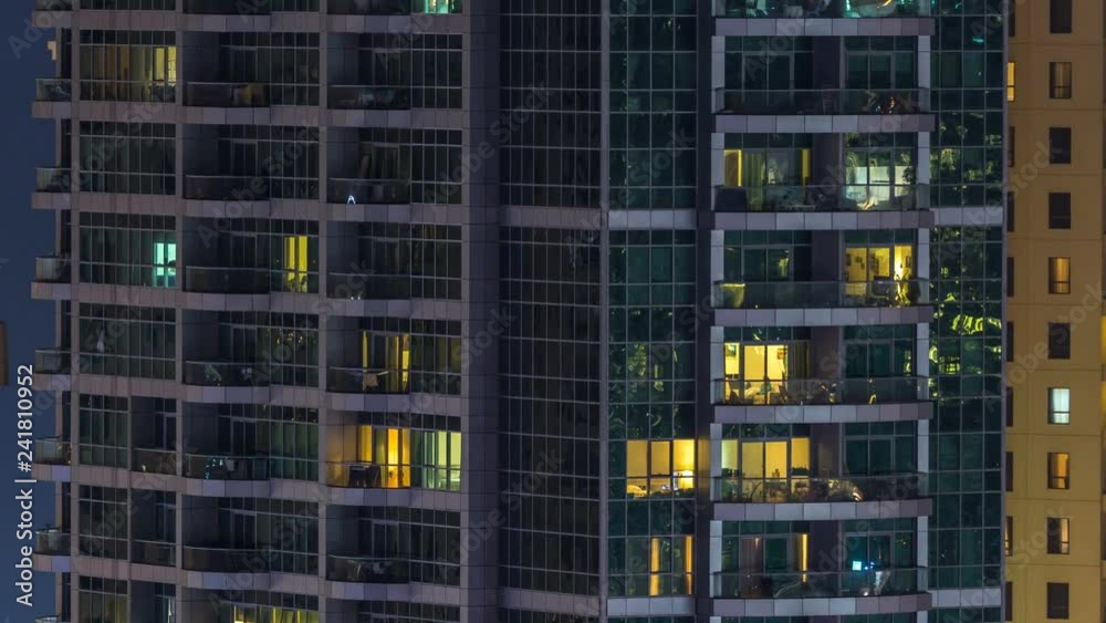 Glowing windows in multistory modern glass and metal residential building light up at night timelapse. Glowing windows in multistory modern glass and metal residential building light up at night timelapse.