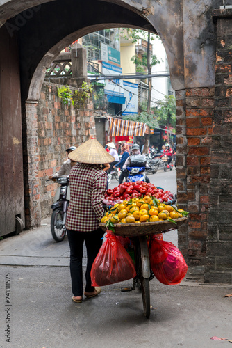 Woman is selling fruits from bicycle on the street in Hanoi Vietnam.