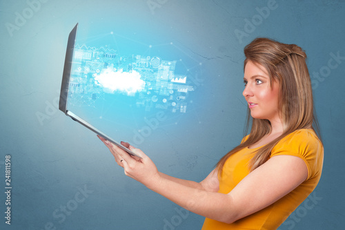 Woman holding laptop projecting notifications, symbols and information based on cloud technology system 