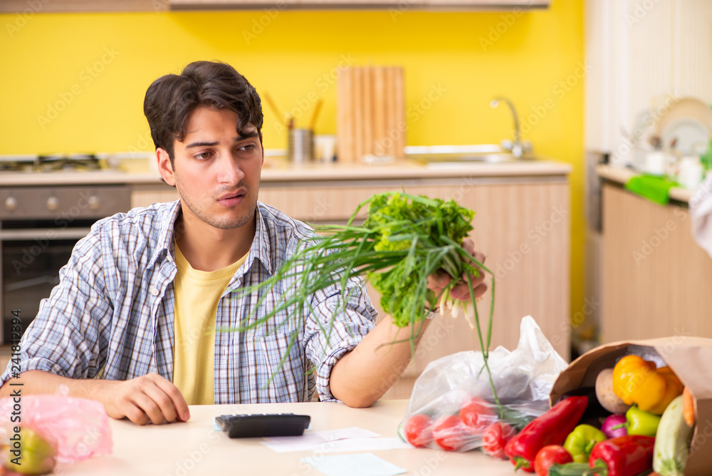 Young man calculating expences for vegetables in kitchen Young man calculating expences for vegetables in kitchen