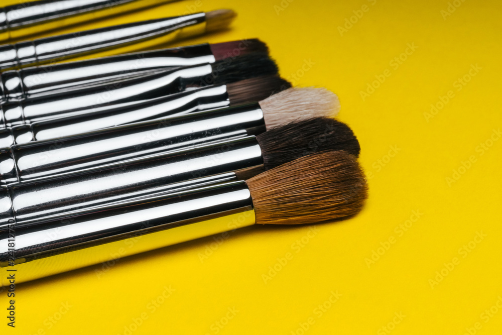Fototapeta premium professional set of red makeup brushes on yellow background with copy space close up