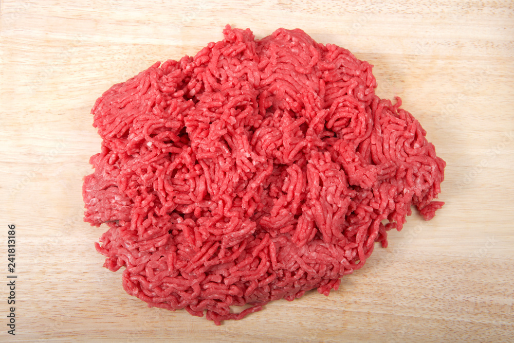 Close up of raw ground hamburger meat low fat, on a light wood cutting table Close up of raw ground hamburger meat low fat, on a light wood cutting table