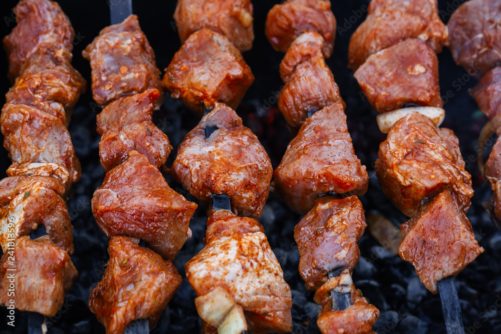 barbecue of pork is prepared on skewers on the grill for a summer picnic